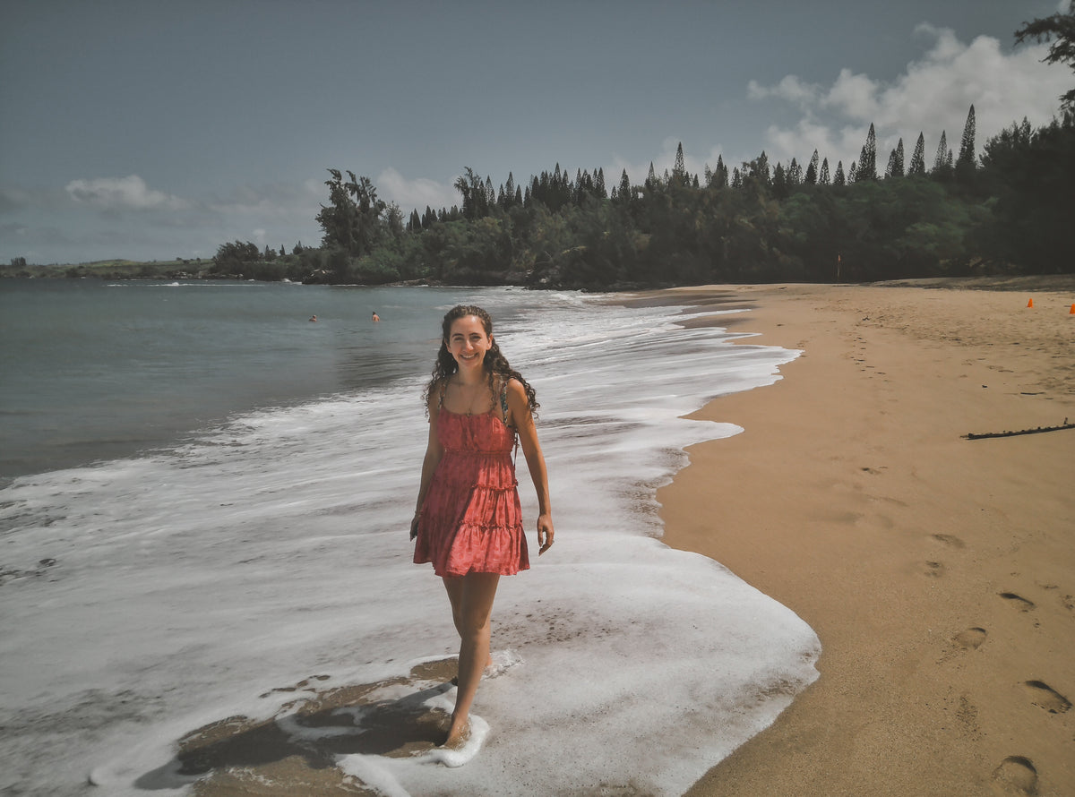 A woman in a red dress at the edge of the surf, photographed on DigiFilm.